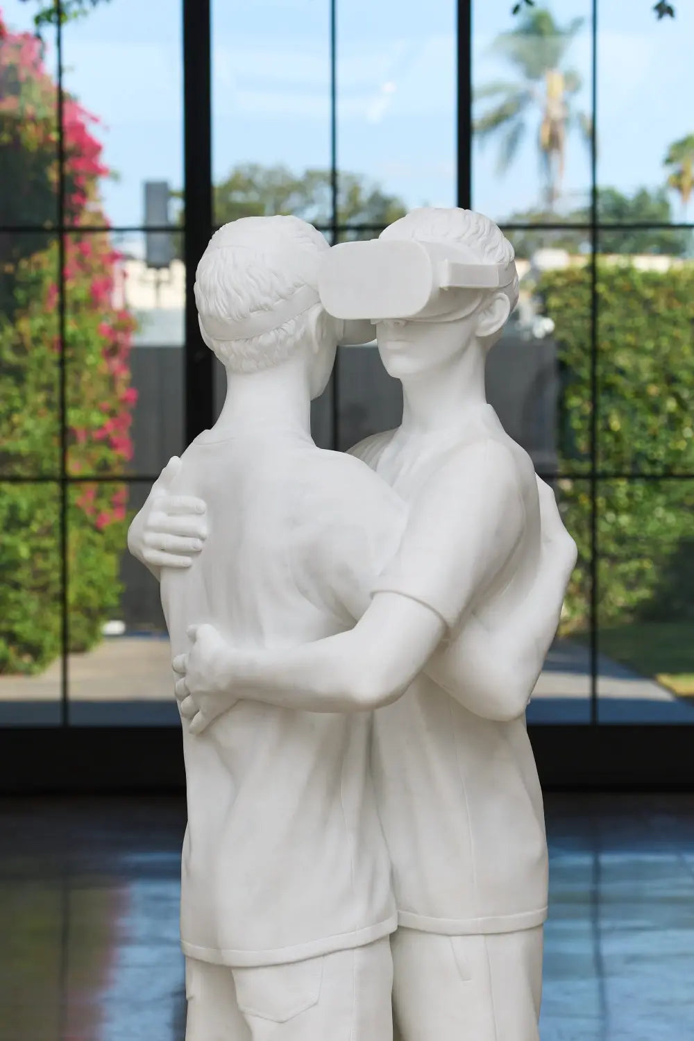 a detail image of a sculpture by Elmgreen and Dragset of two figures embracing, one wears a VR headset