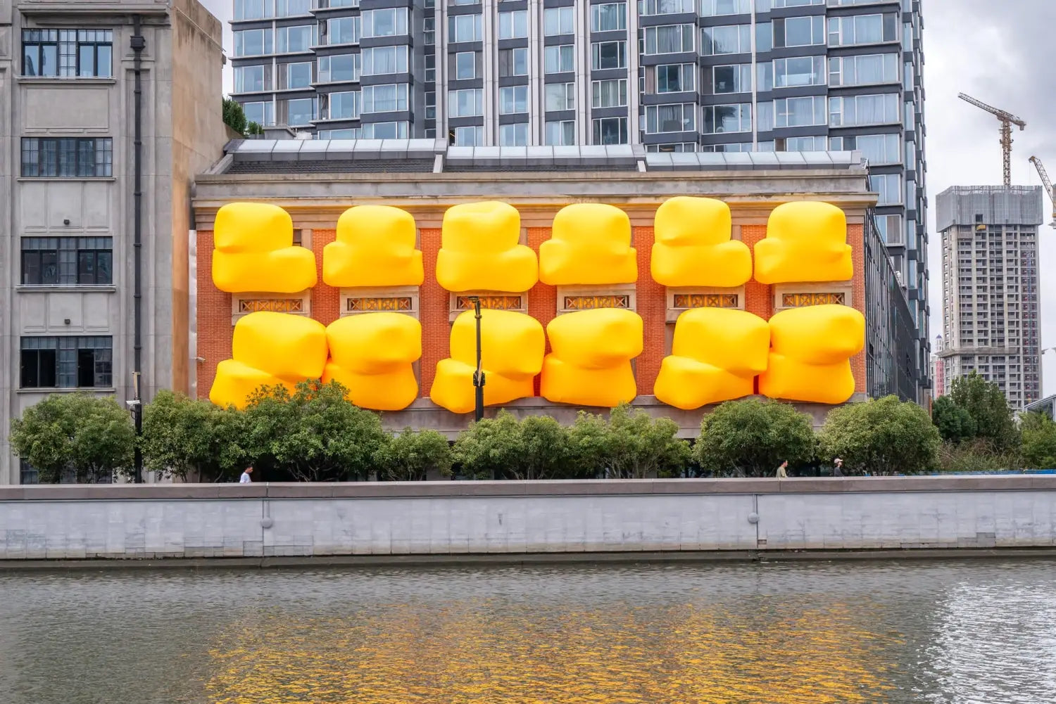 a series of large, yellow, inflatable shapes designed by Steve Messam stick out of apertures in the side of a building