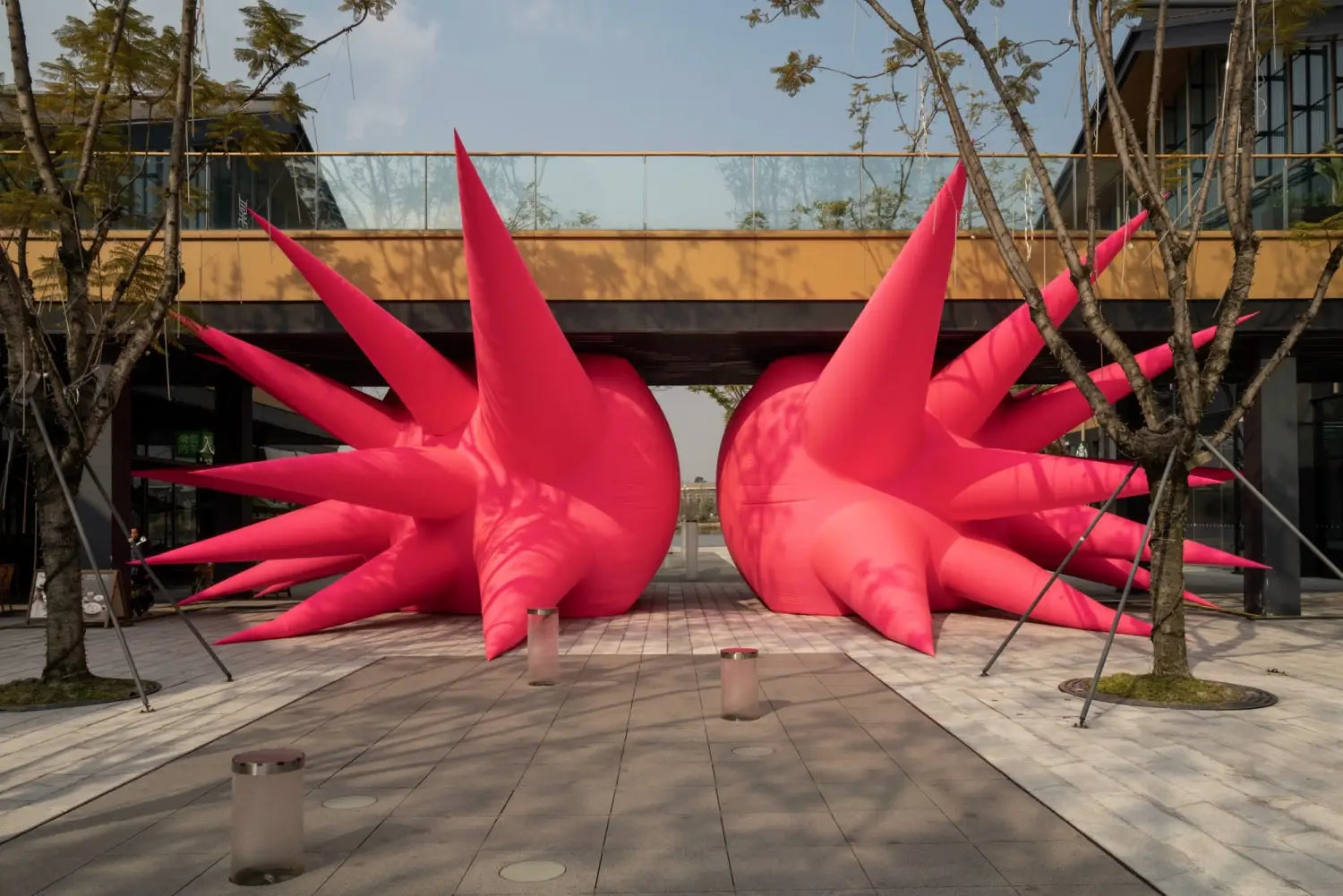 a large-scale inflatable sculpture installation by Steve Messam of two symmetrical, red, spiked forms wedged under a bridge