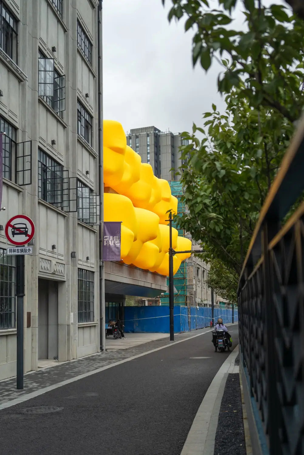 a side view of a series of large, yellow, inflatable shapes designed by Steve Messam stick out of apertures in the side of a building