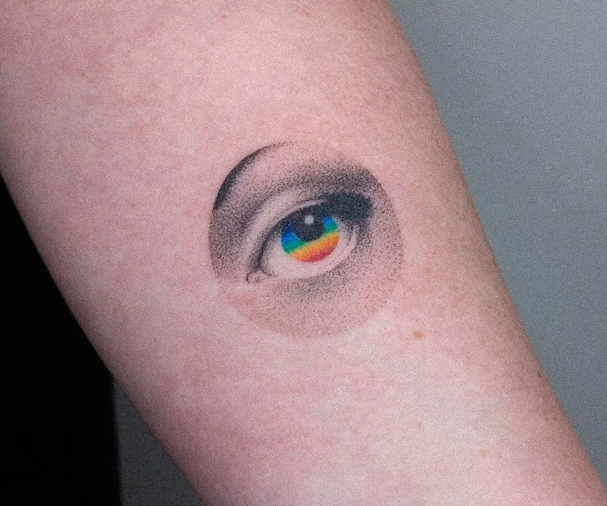 a white arm with a tattoo by Nano Ponto of a vibrant gradient within a black and white eye