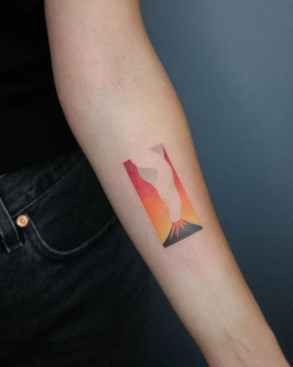 a white arm with a tattoo by Nano Ponto of a vibrant volcano gradient