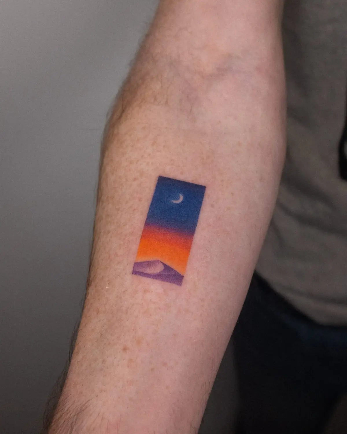 a white arm with a tattoo by Nano Ponto of a vibrant landscape gradient